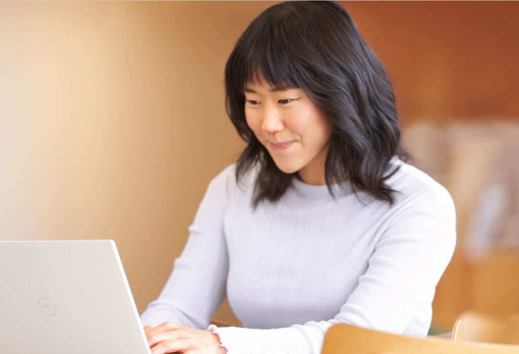 Asian woman smiling while working on her computer