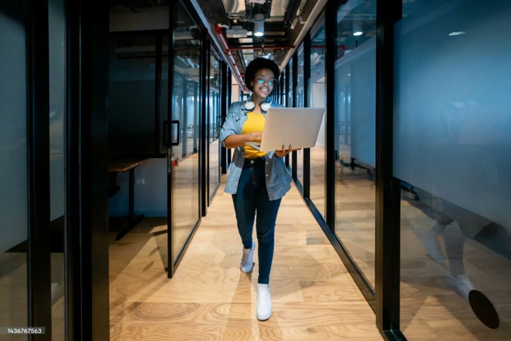 woman in yellow shirt walking with computer
